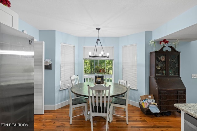 dining room with an inviting chandelier, a textured ceiling, and dark hardwood / wood-style flooring