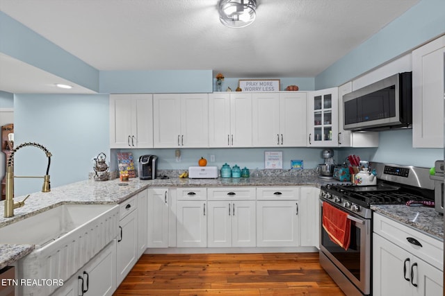 kitchen featuring light stone countertops, sink, dark hardwood / wood-style flooring, stainless steel appliances, and white cabinets