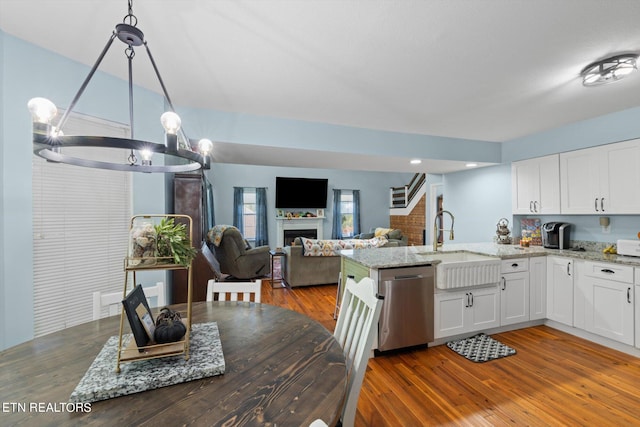 kitchen with white cabinetry, decorative light fixtures, stainless steel dishwasher, and dark wood-type flooring