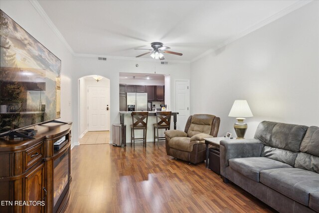 living room featuring dark wood-type flooring, ceiling fan, and ornamental molding