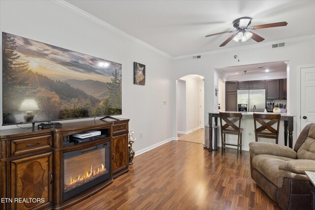 living room with crown molding, dark wood-type flooring, and ceiling fan