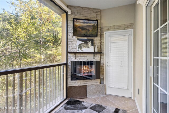 unfurnished sunroom featuring a stone fireplace