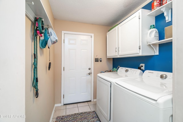 clothes washing area with a textured ceiling, washing machine and dryer, cabinets, and light tile patterned floors