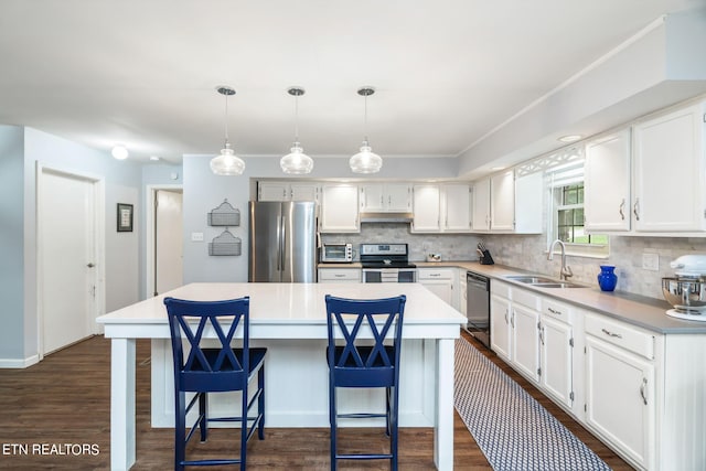 kitchen featuring dark hardwood / wood-style flooring, appliances with stainless steel finishes, a kitchen island, white cabinetry, and sink