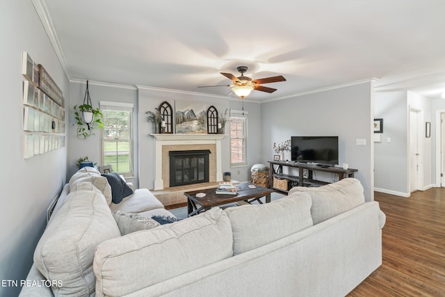 living room featuring crown molding, a tiled fireplace, dark hardwood / wood-style floors, and ceiling fan