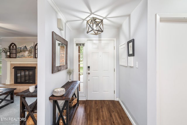 foyer with crown molding, dark hardwood / wood-style floors, a chandelier, and a fireplace