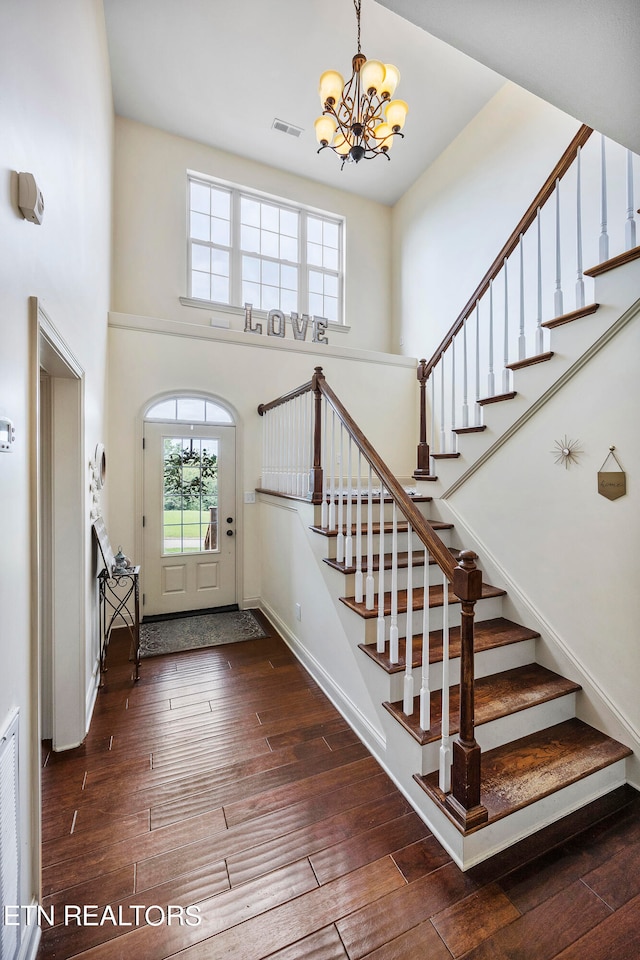 foyer featuring a towering ceiling, a chandelier, and dark hardwood / wood-style floors