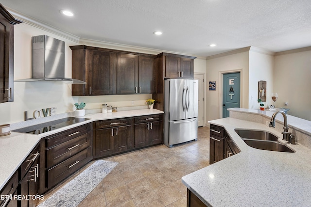 kitchen with black electric cooktop, wall chimney exhaust hood, ornamental molding, sink, and stainless steel refrigerator