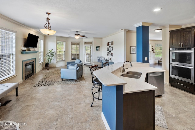 kitchen with a kitchen island with sink, sink, dark brown cabinets, and pendant lighting