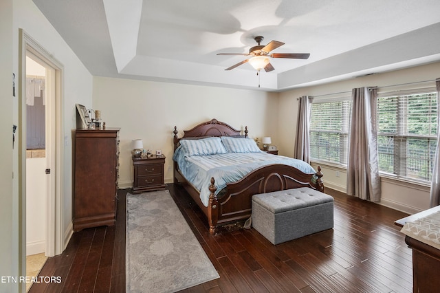 bedroom featuring dark wood-type flooring, ceiling fan, and a tray ceiling