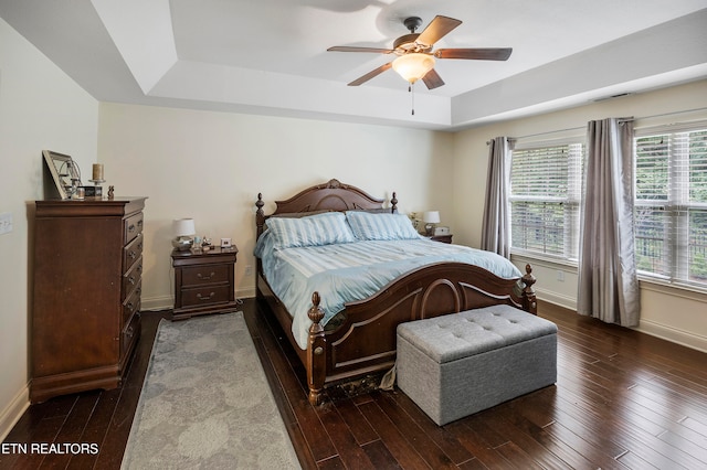 bedroom featuring ceiling fan, a raised ceiling, and dark hardwood / wood-style flooring