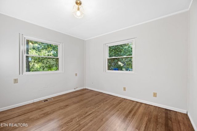 unfurnished room with ornamental molding and hardwood / wood-style floors