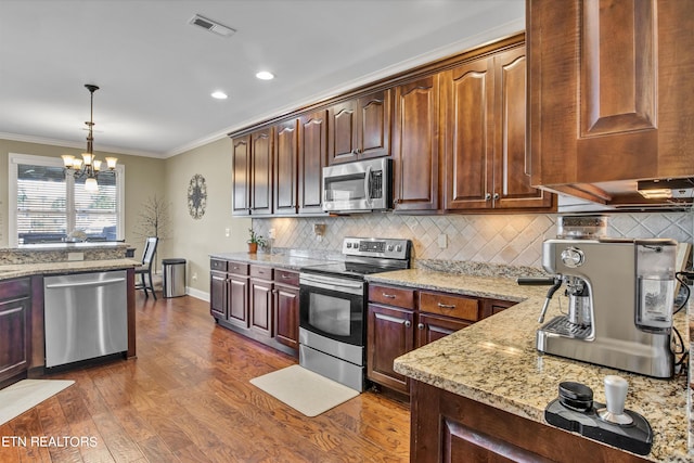 kitchen featuring hanging light fixtures, a notable chandelier, appliances with stainless steel finishes, dark hardwood / wood-style floors, and crown molding