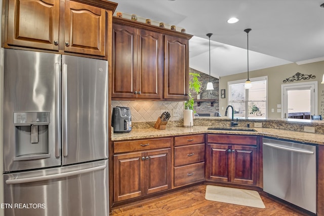 kitchen with decorative backsplash, sink, appliances with stainless steel finishes, light stone counters, and light hardwood / wood-style floors