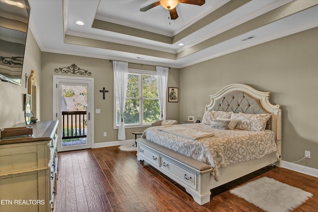 bedroom featuring ceiling fan, dark hardwood / wood-style flooring, access to exterior, a tray ceiling, and ornamental molding