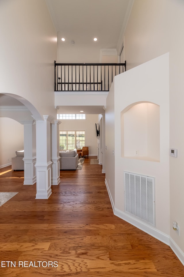 entryway with crown molding, wood-type flooring, and a high ceiling