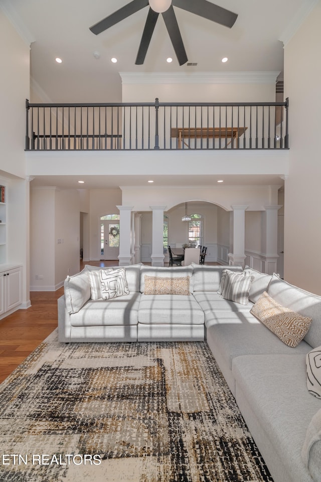 living room featuring ornamental molding, hardwood / wood-style flooring, a towering ceiling, and ceiling fan