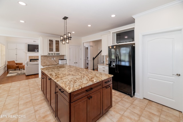 kitchen with a kitchen island, black fridge, backsplash, ornamental molding, and pendant lighting