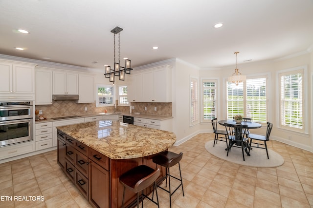 kitchen featuring double oven, backsplash, a center island, a notable chandelier, and white cabinets