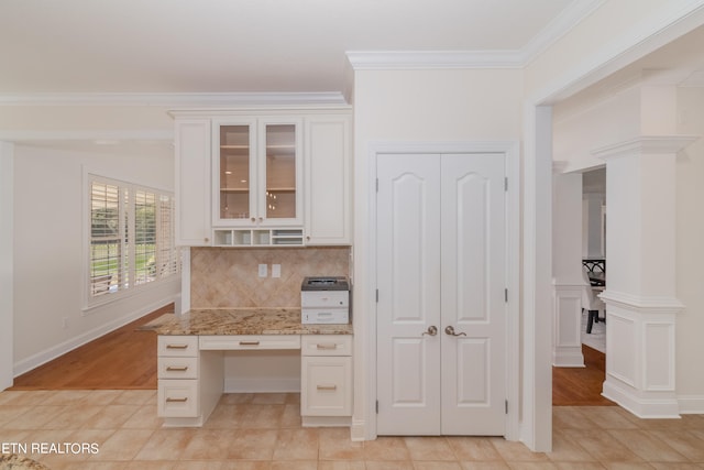 kitchen featuring backsplash, white cabinetry, light hardwood / wood-style floors, crown molding, and light stone counters