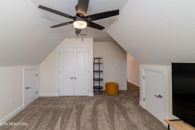 bonus room featuring lofted ceiling, a textured ceiling, carpet, and ceiling fan