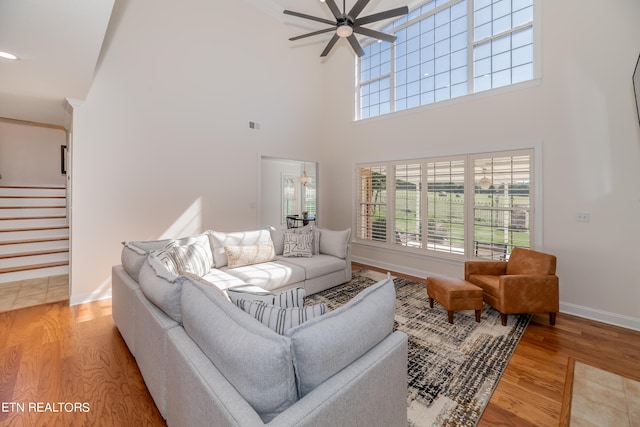 living room with a high ceiling, hardwood / wood-style flooring, and ceiling fan