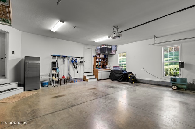 garage with stainless steel fridge and a garage door opener