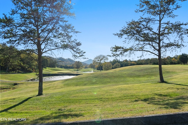 view of property's community featuring a water and mountain view and a lawn