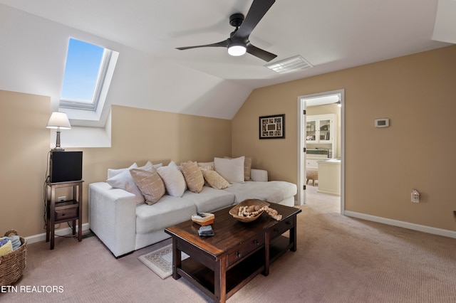 carpeted living room with vaulted ceiling with skylight and ceiling fan