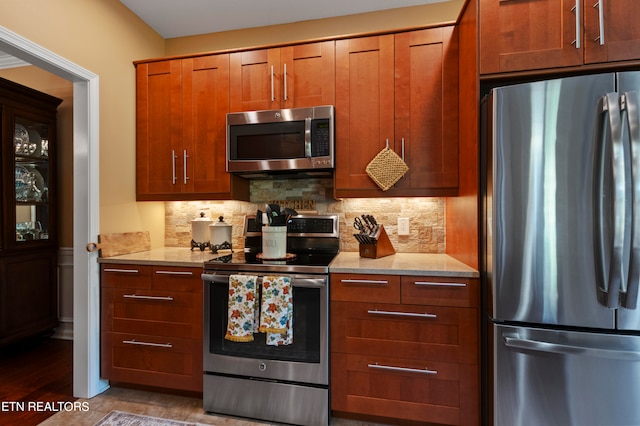 kitchen with backsplash, light stone counters, stainless steel appliances, and dark hardwood / wood-style floors