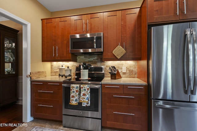 339 Eagles Rdg, Tazewell, TN 37879 - kitchen featuring appliances with stainless steel finishes, decorative backsplash, wood finished floors, light stone counters, and brown cabinets