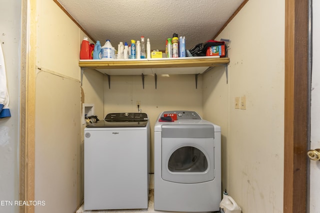 clothes washing area with washing machine and dryer and a textured ceiling