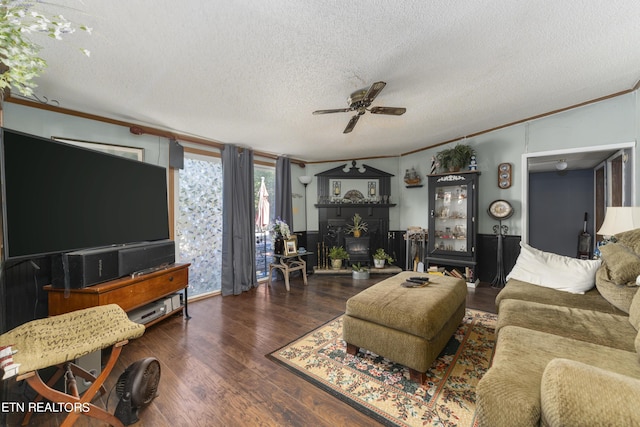 living room featuring dark hardwood / wood-style flooring, a textured ceiling, ceiling fan, crown molding, and a wood stove