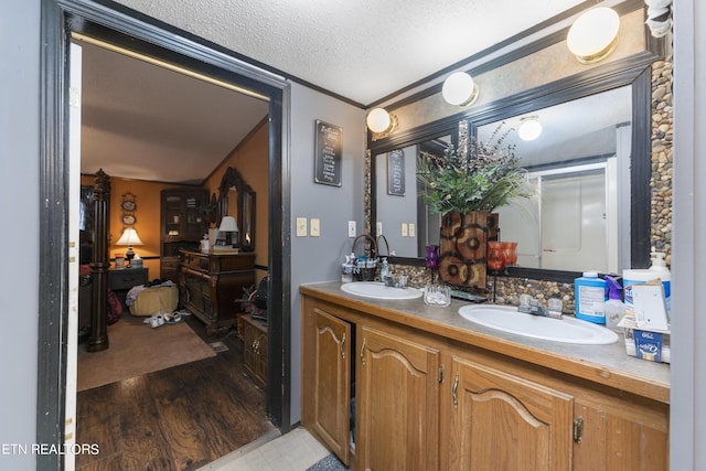 bathroom with hardwood / wood-style floors, vanity, ornamental molding, and a textured ceiling