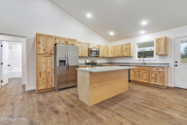 kitchen featuring light stone countertops, sink, light hardwood / wood-style floors, a kitchen island, and appliances with stainless steel finishes