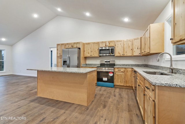 kitchen featuring light stone countertops, sink, appliances with stainless steel finishes, a kitchen island, and hardwood / wood-style flooring