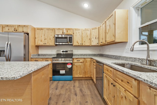 kitchen with light brown cabinets, sink, vaulted ceiling, light wood-type flooring, and appliances with stainless steel finishes