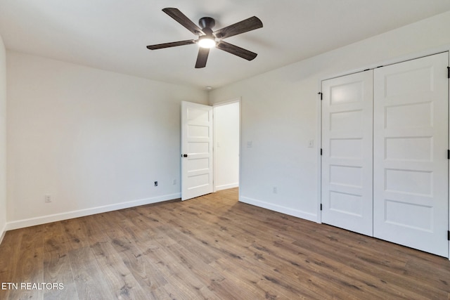 unfurnished bedroom featuring ceiling fan, a closet, and hardwood / wood-style flooring