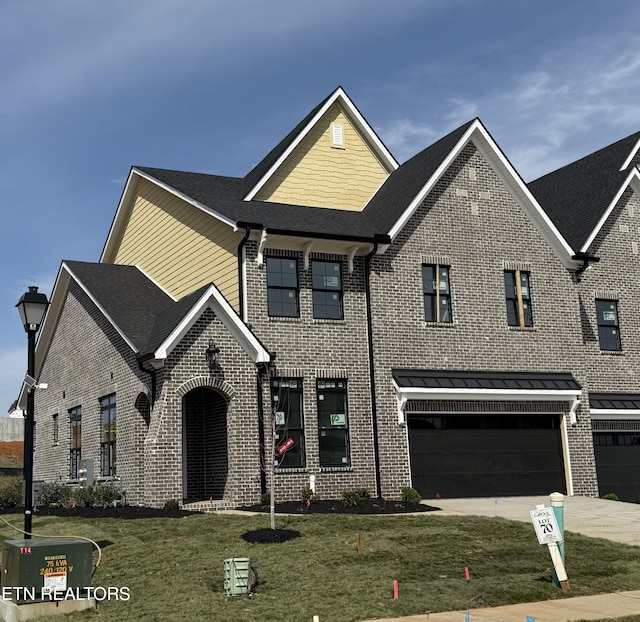 view of front of property with an attached garage, a shingled roof, concrete driveway, a front lawn, and brick siding