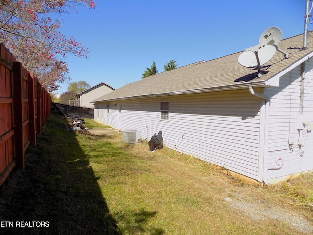 view of side of home with cooling unit and a lawn