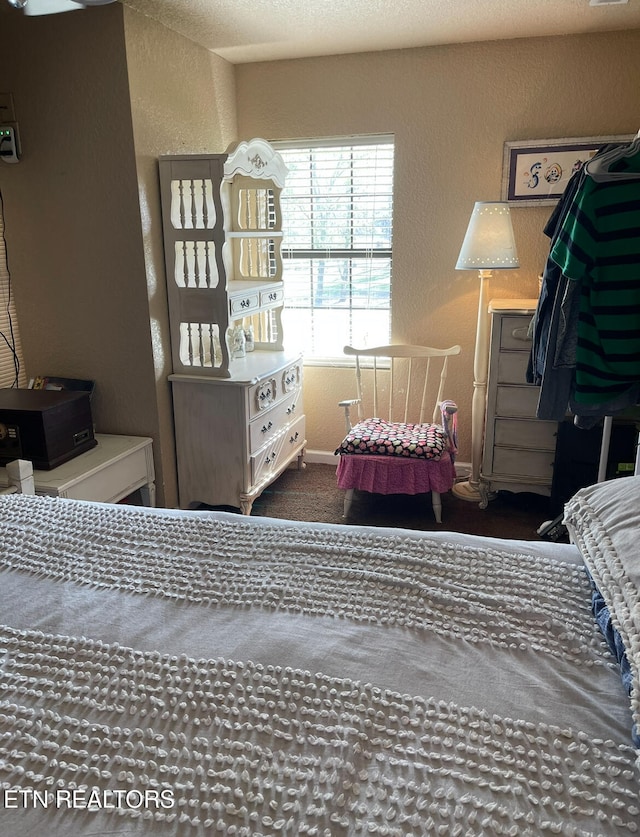 bedroom featuring dark colored carpet and a textured ceiling