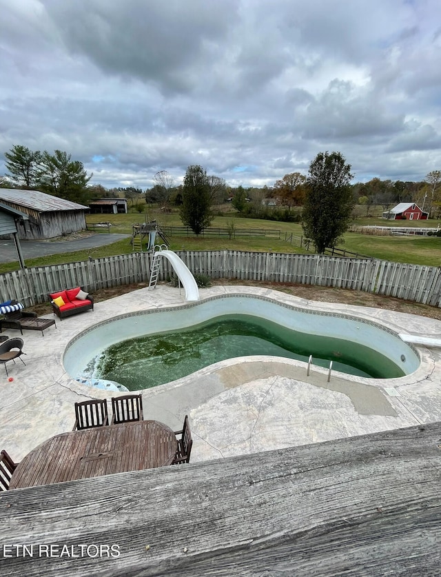 view of pool featuring a water slide and a patio