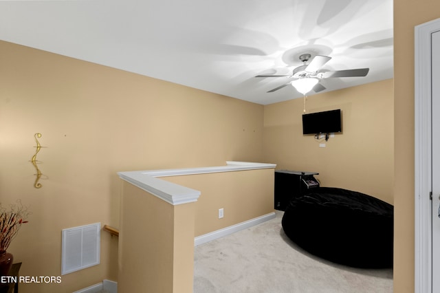 interior space featuring light colored carpet, baseboards, visible vents, and an upstairs landing