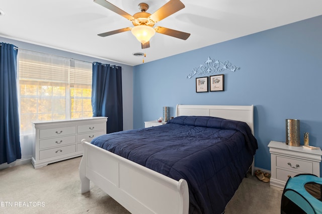 bedroom with light carpet, ceiling fan, visible vents, and baseboards