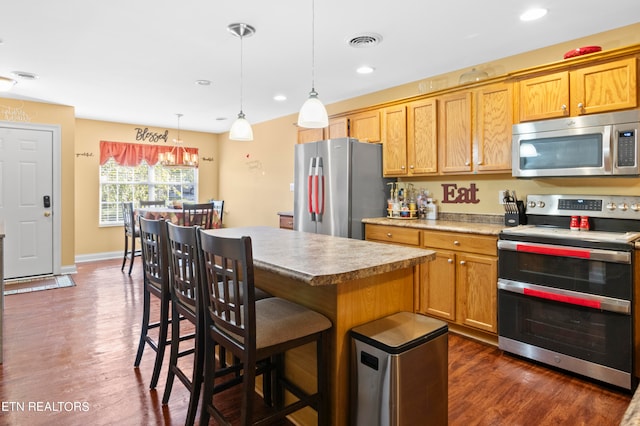 kitchen featuring visible vents, a kitchen island, hanging light fixtures, stainless steel appliances, and light countertops