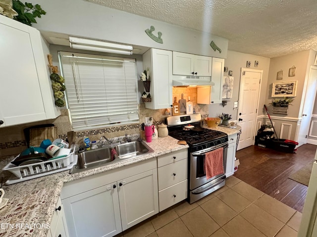 kitchen featuring sink, wood-type flooring, stainless steel gas range oven, and white cabinets