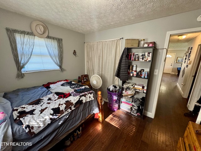 bedroom with dark hardwood / wood-style floors and a textured ceiling