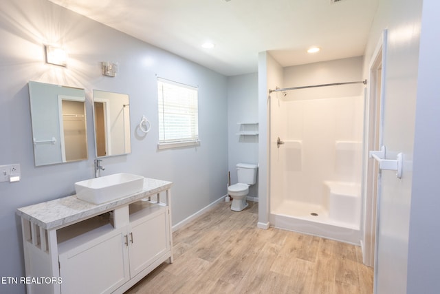 bathroom featuring vanity, hardwood / wood-style flooring, toilet, and walk in shower