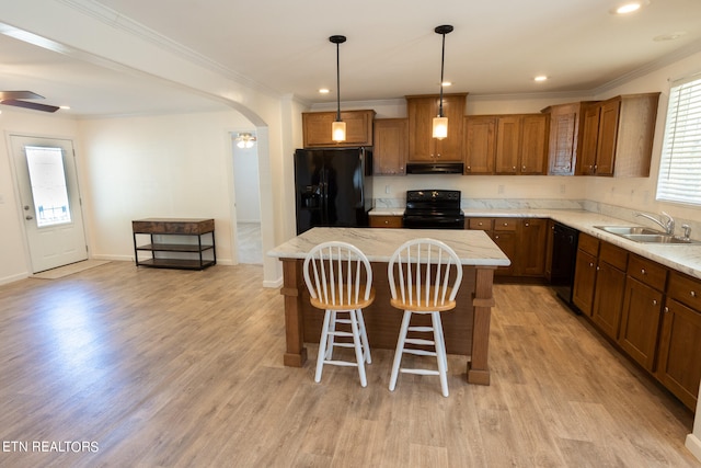 kitchen with sink, light hardwood / wood-style floors, black appliances, and a center island