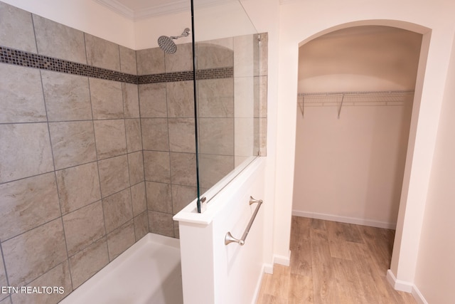 bathroom featuring crown molding, hardwood / wood-style flooring, and tiled shower